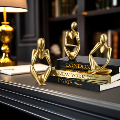 Ensemble de 6 pièces décoratives dorées et noires : livres et statuettes de penseurs. Comprend 3 livres décoratifs et 3 sculptures abstraites de penseurs. Décor idéal pour le salon, une tablette ou une table.
