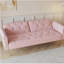 Un canapé-lit de 69,7 pouces de long recouvert de velours rose, doté d'une garniture cloutée et d'un coussin décoratif assorti