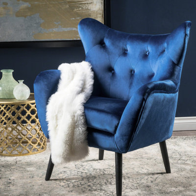 Le fauteuil avec accoudoirs en velours bleu marine grésillant avec fauteuil à oreilles ajoute un élément chic à votre maison