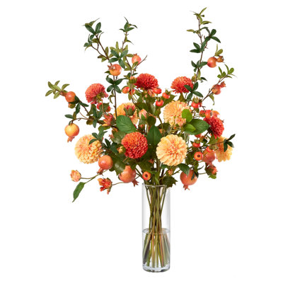 Dahlias oranges et branches de grenade dans un grand vase en verre