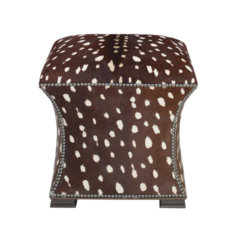 Square ottoman upholstered in a brown and white spotted faux hide fabric featuring nailhead trim detailing.