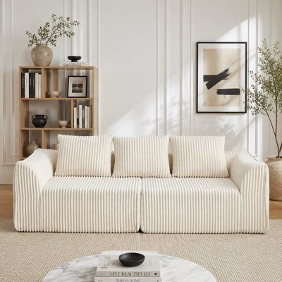 Canapé minimaliste en velours côtelé 3 places avec dossier ergonomique et accoudoirs courbés, comprenant trois coussins décoratifs en forme de corne