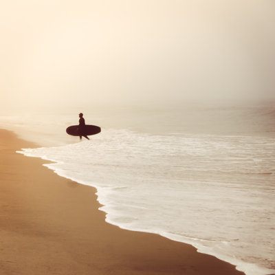 Silhouette d'un surfeur sur une plage brumeuse