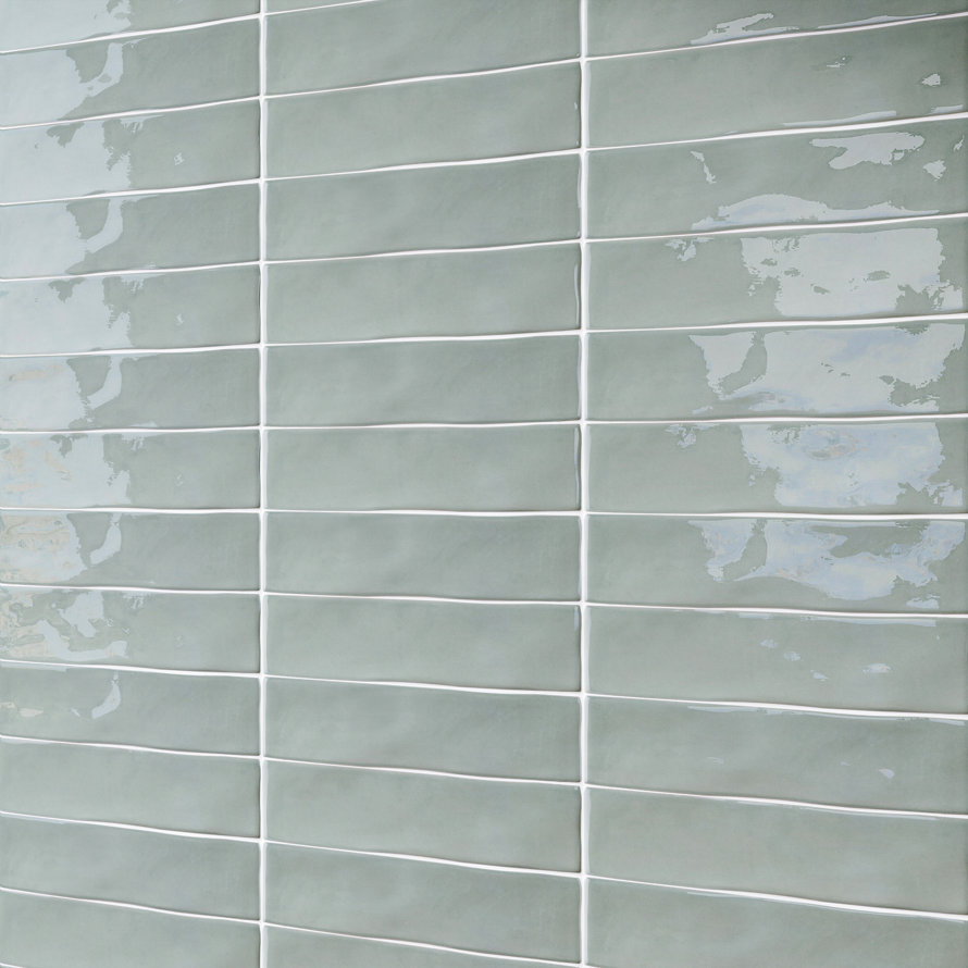 Sage green rectangular subway wall tiles with a glossy, undulating surface and white grout lines.