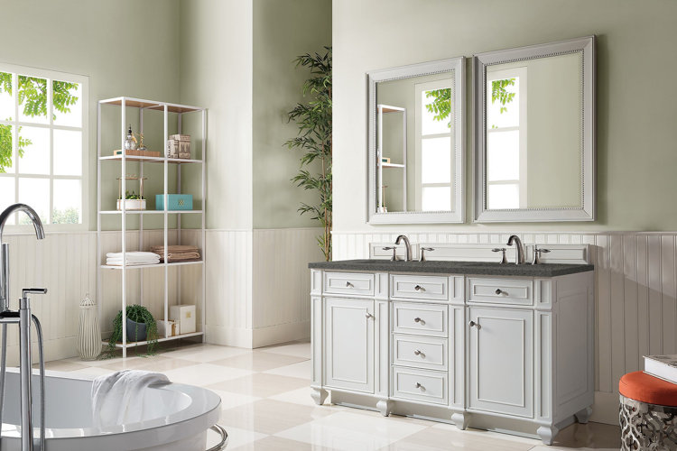 White farmhouse bathroom design with white shiplap walls, vanity, and bath. Shelves with bathroom accessories. Two framed mirrors above the vanity