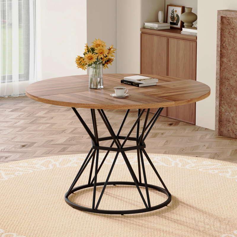 Une table de salle à manger circulaire d'un diamètre de 47,3 pouces, comprenant 4 plateaux de table en MDF grain de bois de noyer, des supports en métal en forme de sablier noir et une table de salle à manger de style industriel moderne pour 4 à 6 personnes.