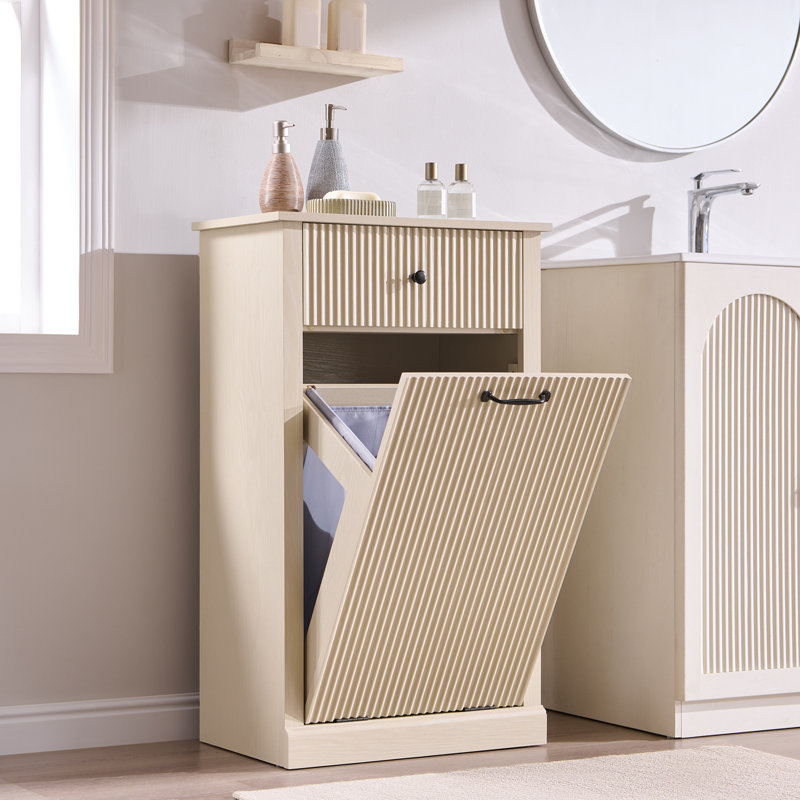 Natural wood laundry hamper cabinet with a tilt-out storage compartment and a single drawer, featuring a fluted ribbed design.