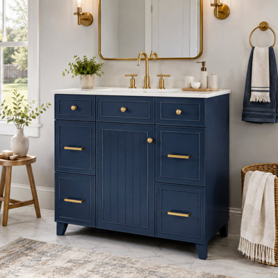 Meuble-lavabo de style transitionnel avec lavabo en céramique, structure en bois massif, portes à fermeture amortie, étagères réglables, trois tiroirs et rangement double profondeur pour sèche-cheveux, idéal pour la salle de bain ou les toilettes.
