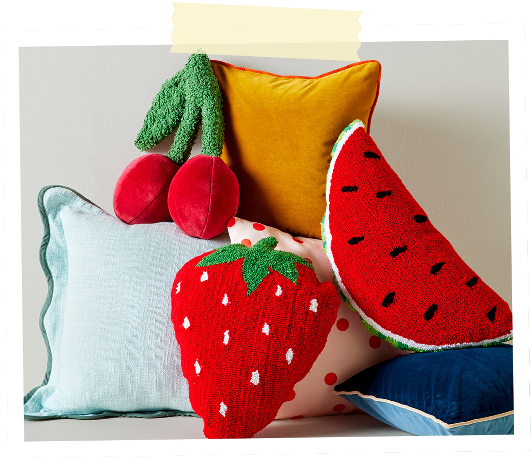 Une pile de coussins décoratifs colorés en forme de fraise, de cerise et de tranche de melon d'eau.