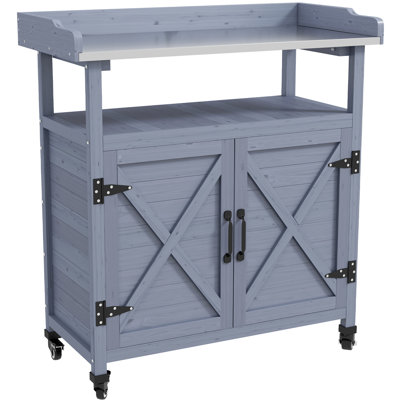 Table de rempotage grise avec rangement. Structure en bois. Plateau en aluminium. Roulettes en caoutchouc pour faciliter le déplacement. Aspect rouille. Parfait pour le jardin. Dimensions : 83,3 cm (l) x 40,6 cm (p) x 95,2 cm (h). Table d'extérieur. Conception rouille. Convient au jardin.