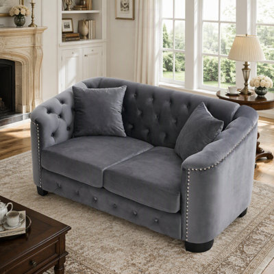 Canapé Chesterfield moderne en velours gris, 2 places, 150 cm, avec dossiers capitonnés, accoudoirs cloutés et 2 coussins. Parfait pour un salon, une chambre, un appartement ou un bureau.