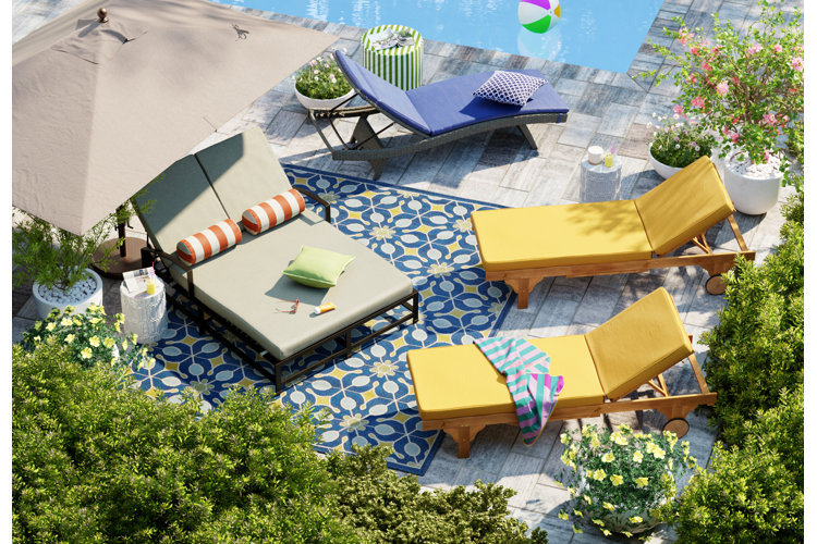 teak lounge chairs with plush outdoor cushions, a square-shaped outdoor umbrella, and a side table