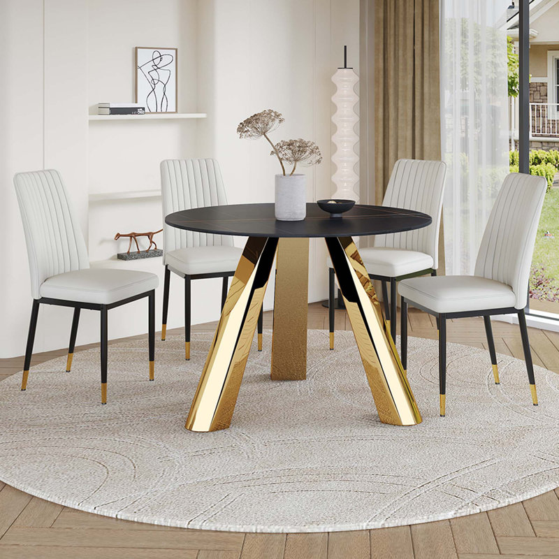 Une table de salle à manger ronde de 42 pouces avec un plateau en granit et des pieds en acier inoxydable, jumelée à quatre chaises de salle à manger en polyuréthane