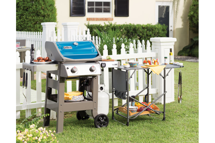 blue gas grill in front of a white picket fence
