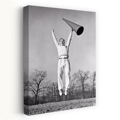 Adolescent exubérant des années 1930, jeune homme vêtu d'un chandail blanc portant des chaussures de sport, une pom-pom Girl du Collège sautant et tenant un mégaphone