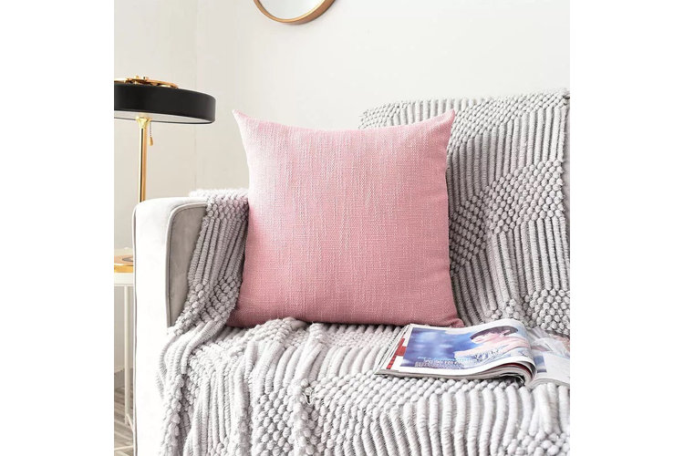 Pink throw pillow and gray throw blanket on a sofa.