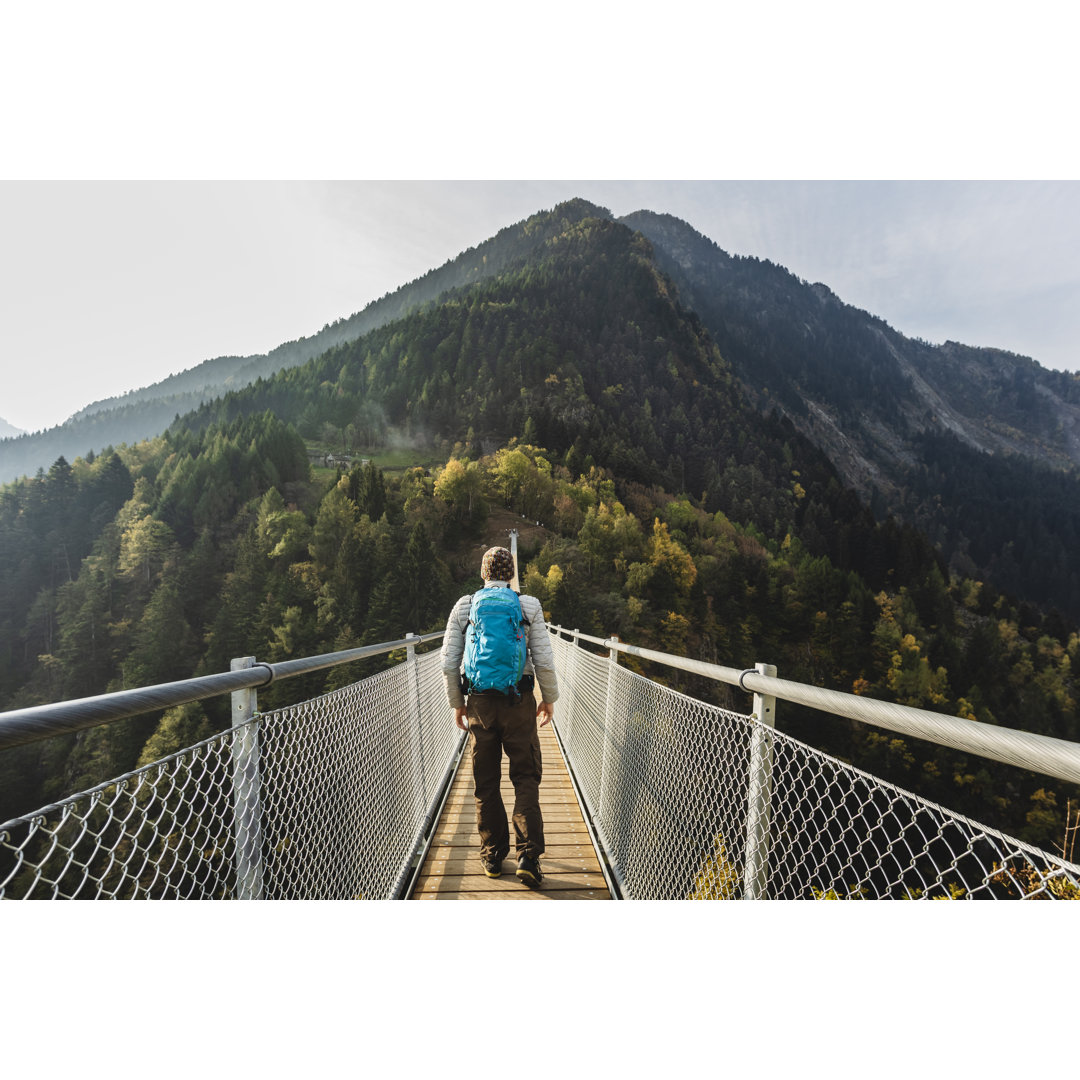 Solo-Wanderer auf Hängebrücke zwischen zwei Bergtälern