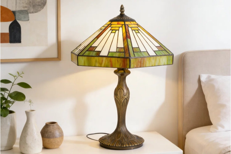 bronze Tiffany lamp with a geometric stained glass shade on a white nightstand