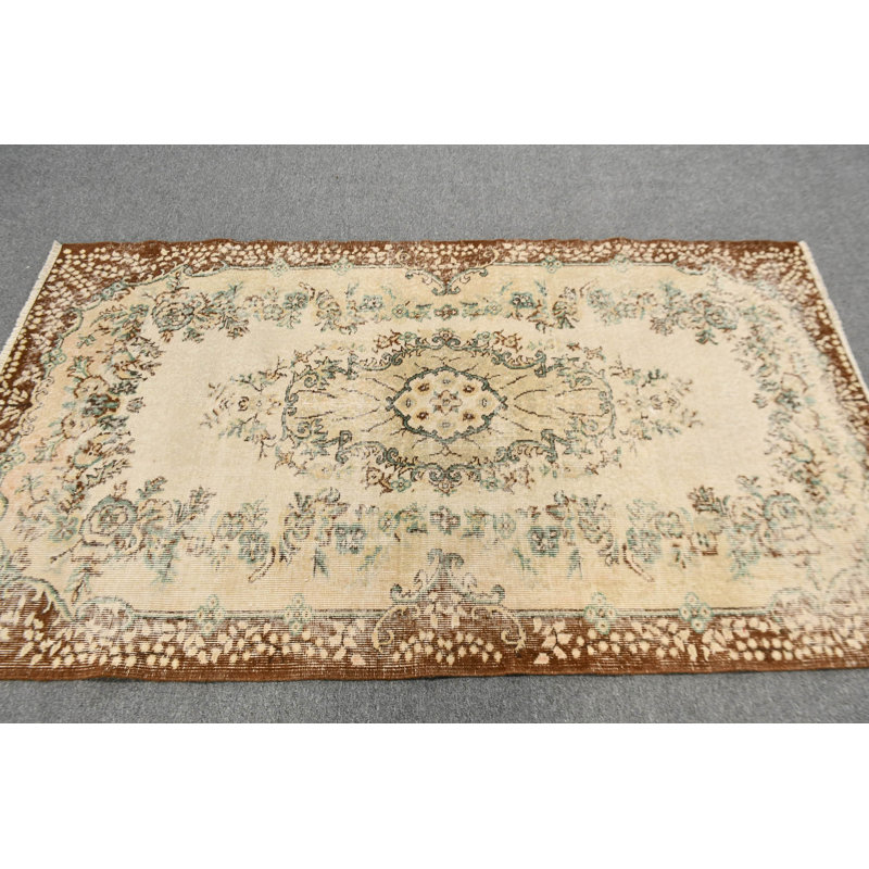 Tapis turc de style antique avec un élégant motif floral dans des tons bruns et beiges, idéal pour un décor traditionnel