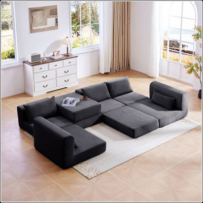 Ensemble de canapés d'angle modulaires et rembourrés avec cinq coussins pour un agencement flexible et un confort optimal dans votre salon.