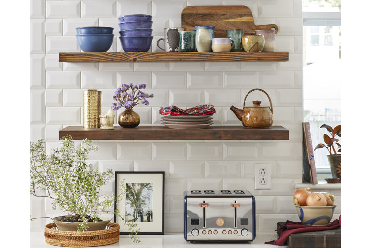 Kitchen with white tiling and open wood shelving to display dinnerware and decor.