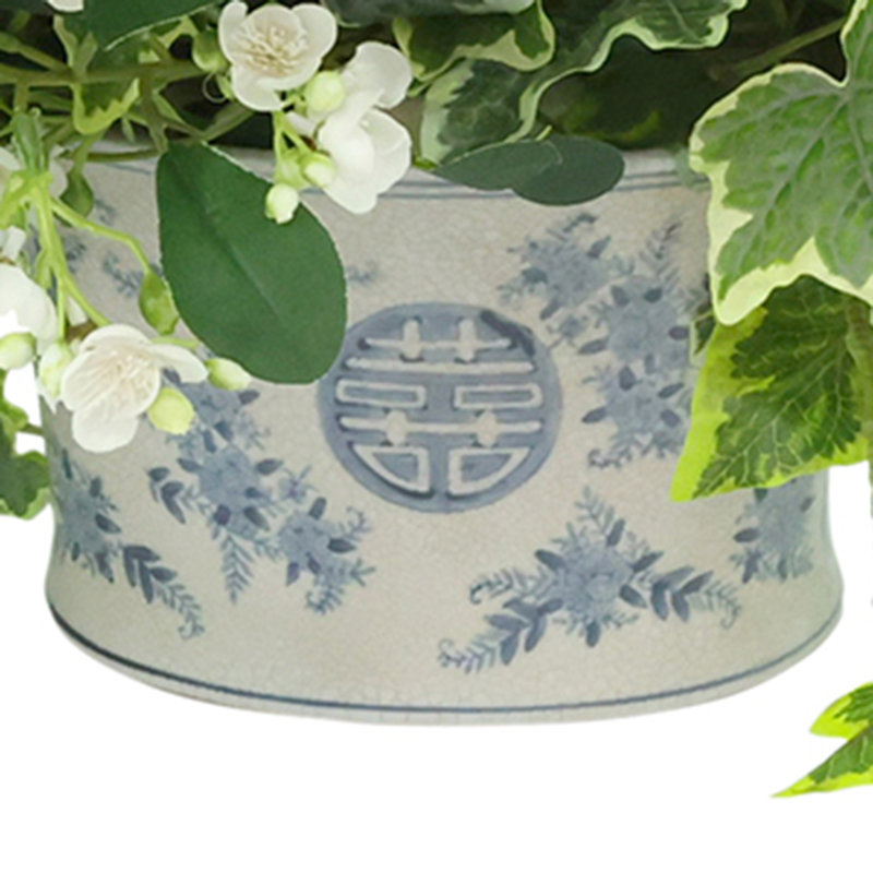 Lierre panaché et fleurs en herbe dans un vase décoratif