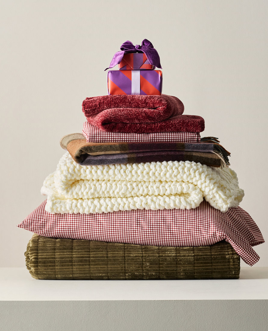 Stack of blankets, pillows, and a gift.