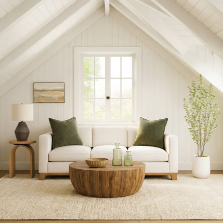 White couch with green pillows and a wooden coffee table