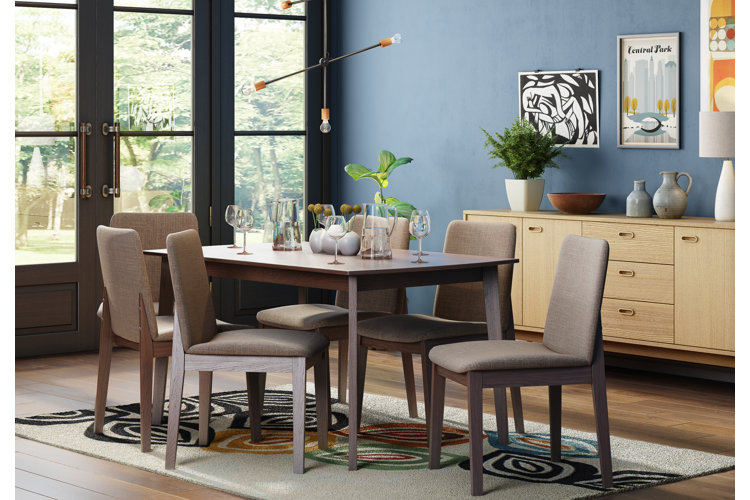 mid-century modern style dining room with a geometric patterned rug, abstract art, and a wood table and chairs