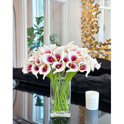 Arrangement floral fausses fleurs de lys mauves dans un vase en verre