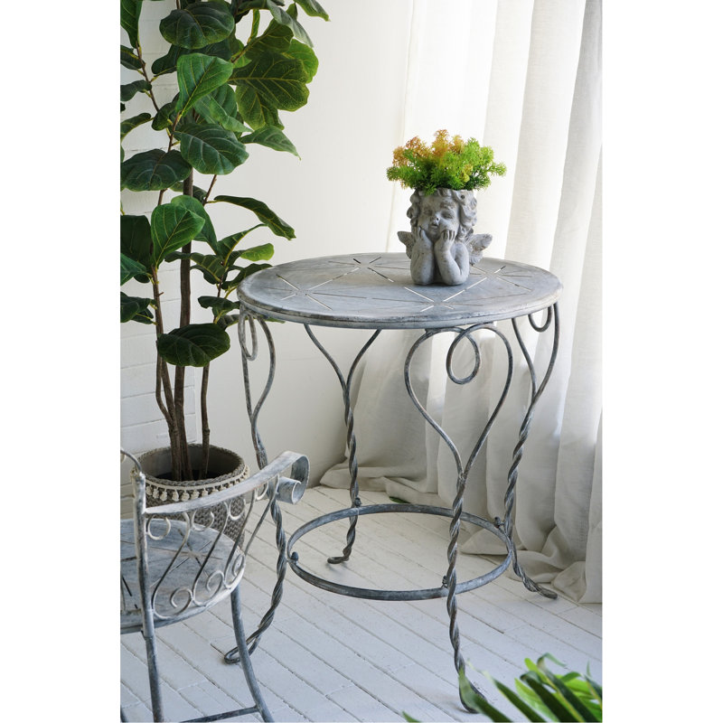Table d'appoint ronde en fer de style campagne française (66 x 66 x 76 cm), fini argent vieilli, pieds torsadés et tablette inférieure pour petits objets. Pieds en forme de cœur. Parfait pour la décoration de terrasse.
