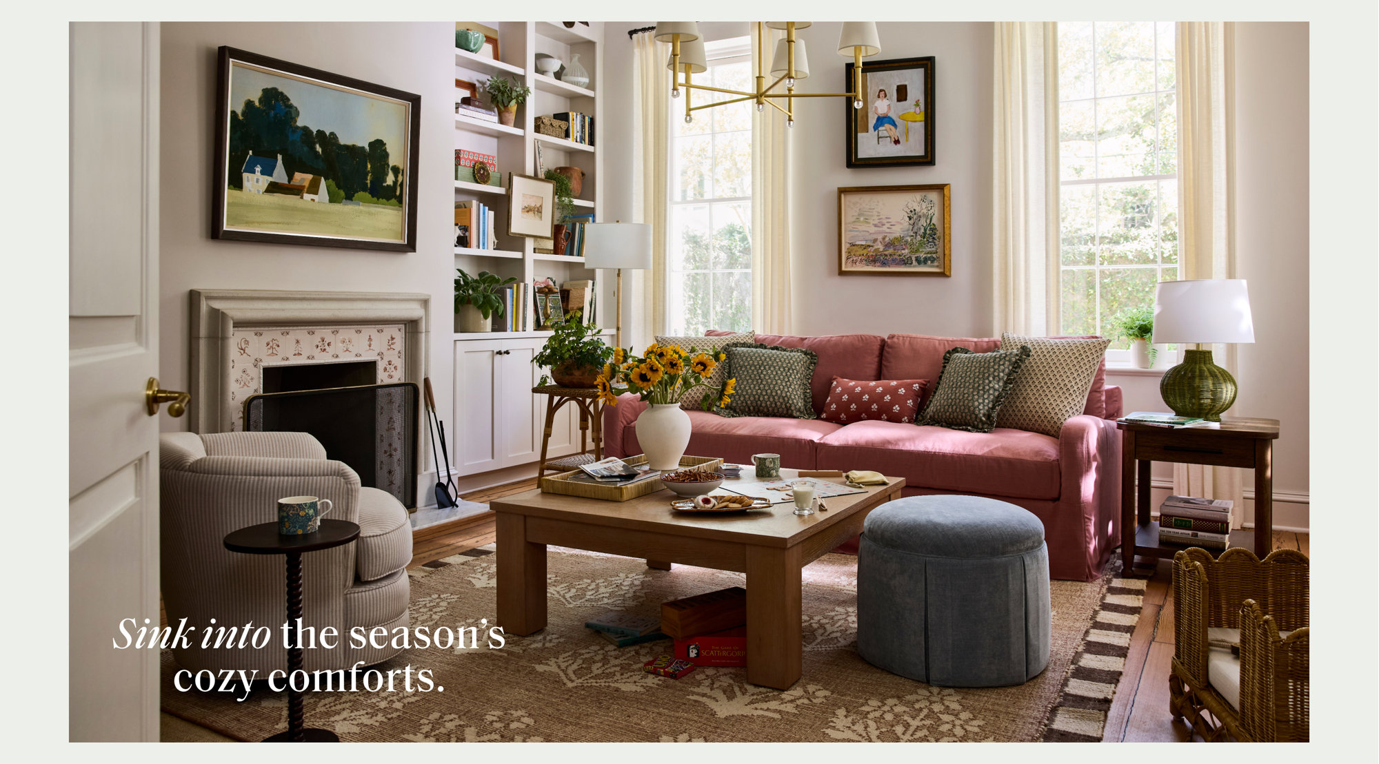 Sink into the season's cozy comforts in a bright living room featuring a pink sofa, wooden coffee table, and blue pleated ottoman.