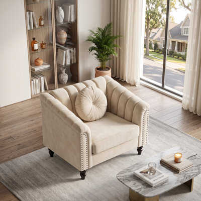 Fauteuil capitonné blanc, avec accoudoirs arrondis et garniture cloutée.