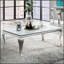 Table basse contemporaine avec plateau en verre blanc et structure en métal argenté, parfaite pour les salons modernes