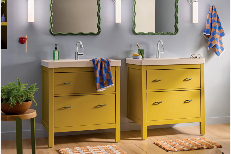 modern bathroom with two mustard yellow vanities, green mirrors, and checkered blue and orange towels