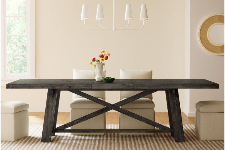 modern farmhouse dining room with dark wood trestle table, cream upholstered chairs, striped area rug, and white chandelier