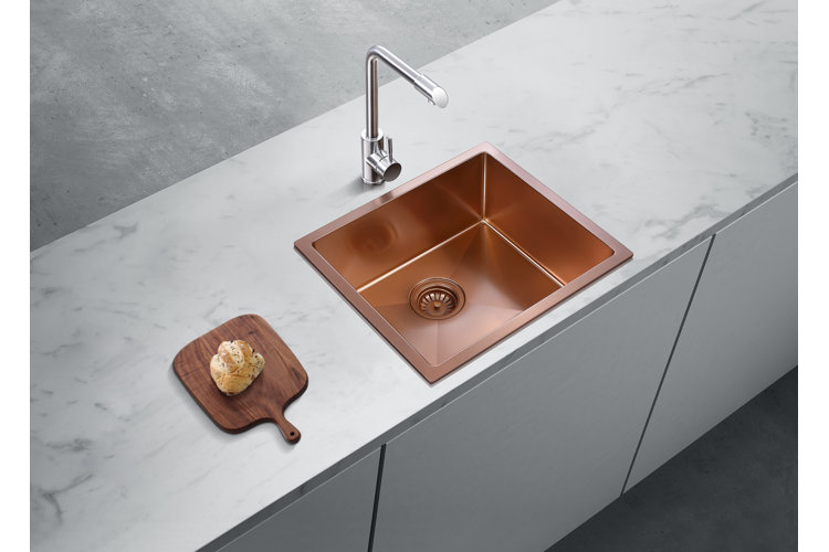 a copper drop-in sink in a marble counter top