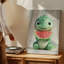 Toile, un adorable personnage de dinosaure assis avec une expression ludique tenant une grande tranche de melon d'eau-920226367