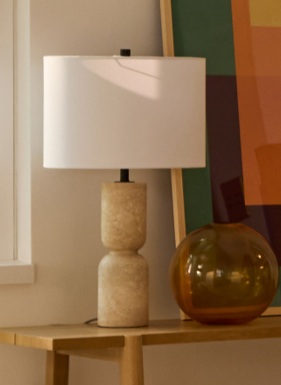 Table lamp with a travertine base and white shade.