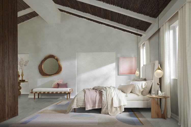 Modern style bedroom with neutral color palette pink and blue geometric area rug and light wood nightstand and bench