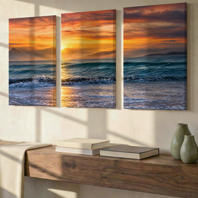 Ensemble de 3 toiles grand format exclusives représentant un coucher de soleil orange sur l'océan. Décoration murale moderne haut de gamme pour salon, chambre, bureau et maison. Prêtes à être accrochées.