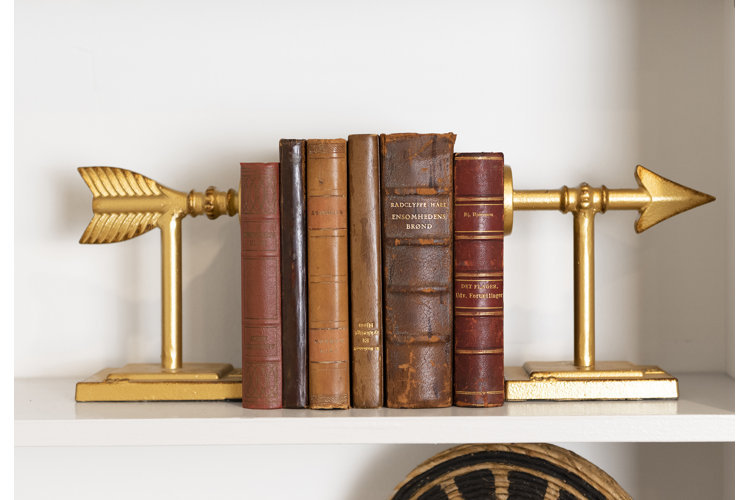 Gold arrow shaped book ends with colorful books in between them