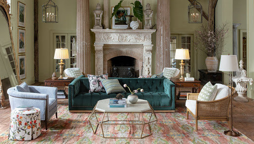 A living room with a velvet sofa, linen armchair, and wicker accent chair.