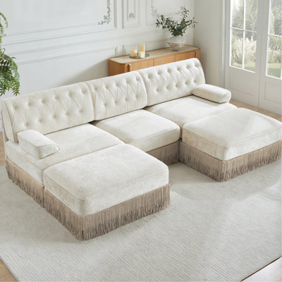 Canapé d'angle 3 places en velours beige en forme de U, élégant, à franges et boutons, modulable, idéal pour repenser votre chambre et réaménager votre intérieur de façon ergonomique et modulaire.