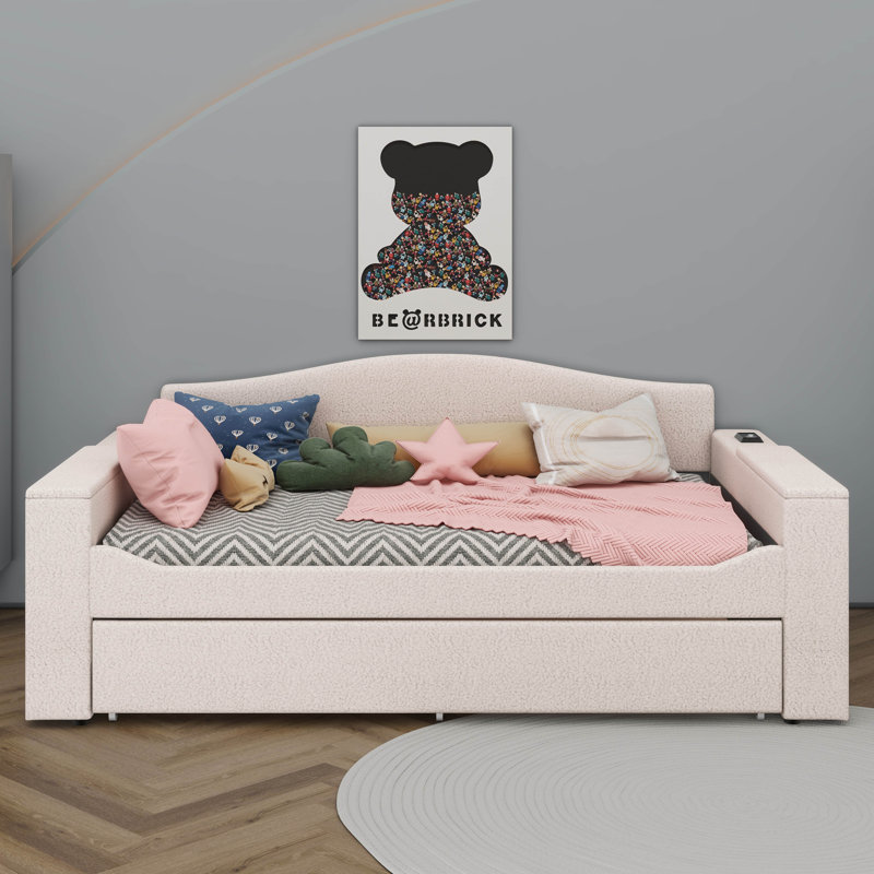 Un lit de jour rembourré avec accoudoirs de rangement, un lit gigogne sous le lit et un système audio Bluetooth de pointe