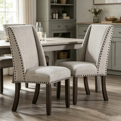 Élégantes chaises de salle à manger rembourrées à haut dossier avec garniture cloutée et pieds en bois massif