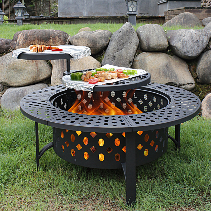 A black round fire pit with two attached round tables with food on them