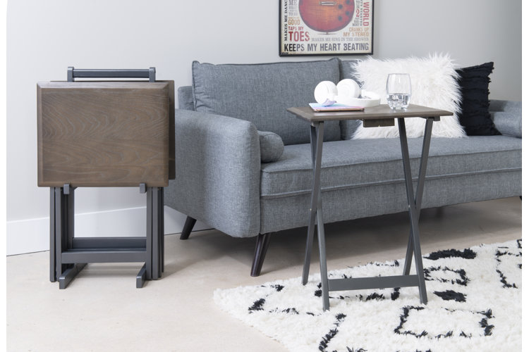 a tray table in front of a couch with a second one folded in the corner