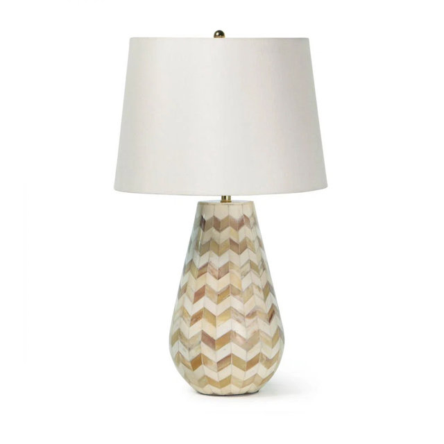 Table lamp with a tear-drop shaped base featuring a beige and brown chevron inlay pattern and a white fabric drum shade.