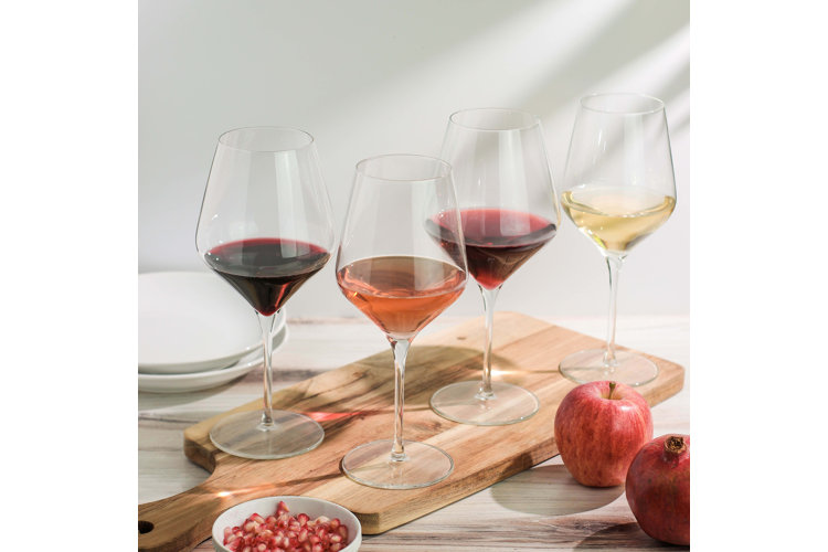 Four glasses of red, rose, and white wine on a wood serving platter.